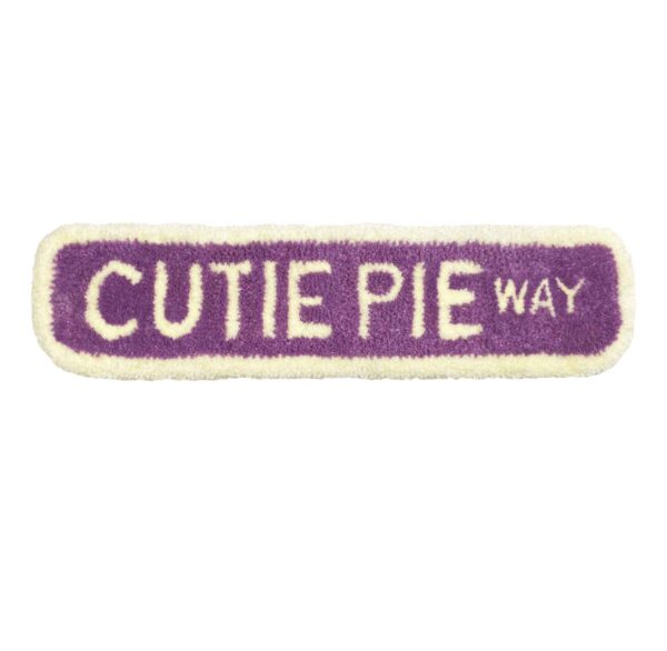 purple tufted road sign that reads "CUTIE PIE WAY"